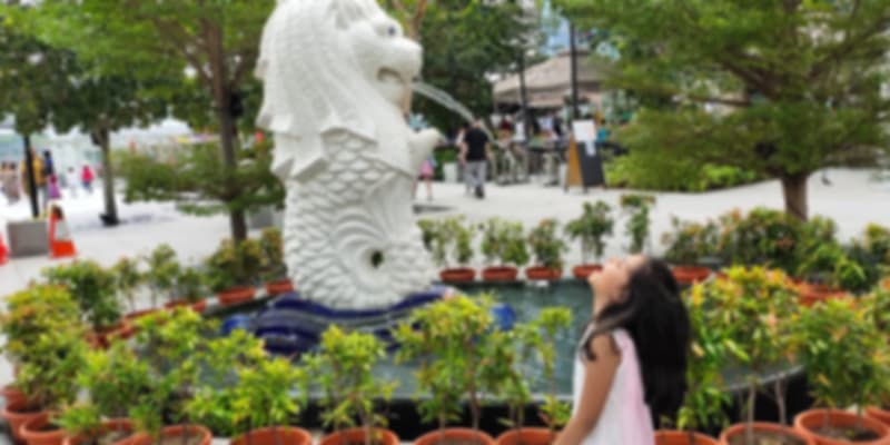 My daughter posing with the lion during our family vacation to Singapore