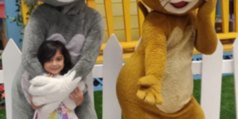 A picture of a cute little kid hugged by a mickey mouse on their family trip to Dubai