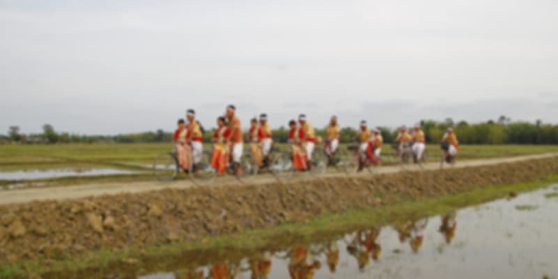 A group of people riding in bicylces in traditional clothes in one of the festivals of Assam