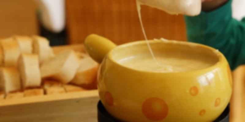 Traditional Swiss cheese fondue served in a pot with bread cubes, a must-try Swiss street food classic.