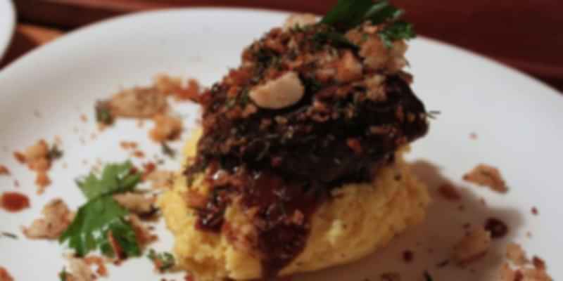 Polenta topped with tender Swiss braised beef, garnished with herbs and toasted crumbs—a specialty from Ticino.
