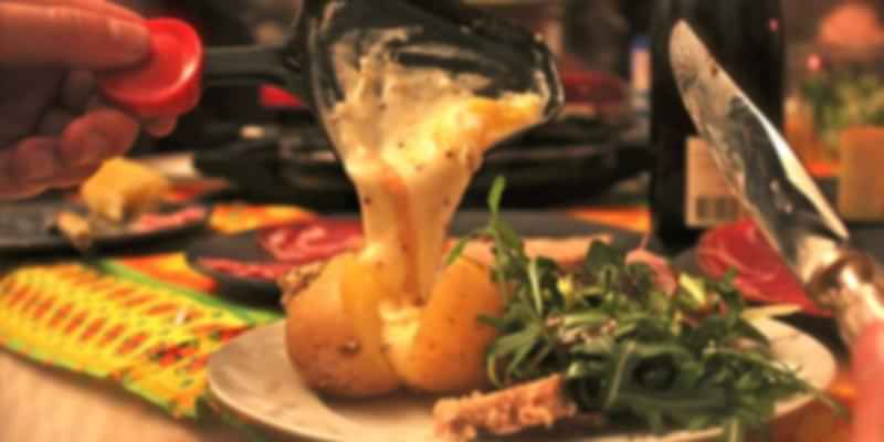 Melted Swiss raclette cheese being scraped over vegetables and bread, a popular street food at Swiss markets.