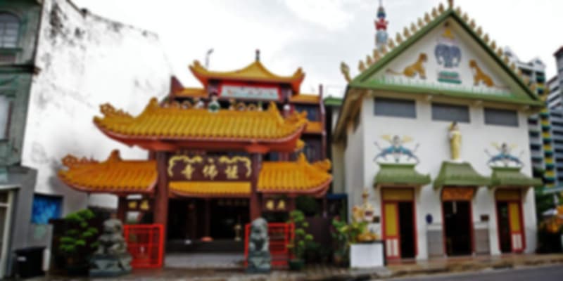 Front view of Sakya Muni Buddha Gaya Temple in Singapore, with Thai architectural elements and a large golden Buddha statue inside.