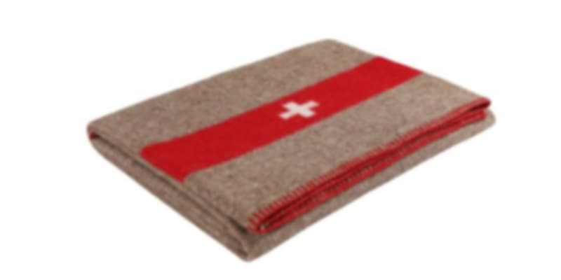 A folded, brown Swiss army blanket with a red stripe and white cross in the center, resting on a plain white surface