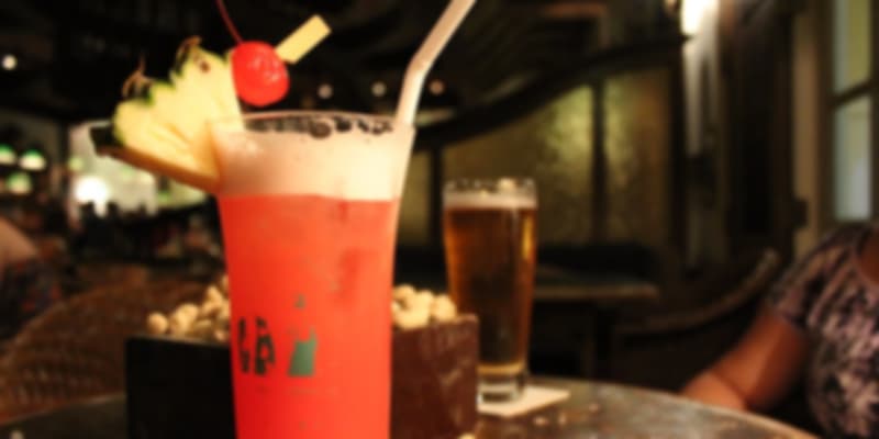 Iconic Singapore Sling cocktail garnished with cherry and pineapple, served at a bar.