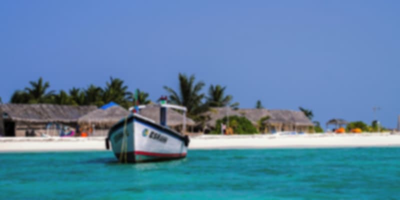 Fishing boat anchored near the white sandy beach and turquoise waters of Lakshadweep