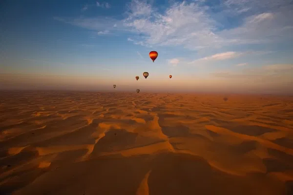 Desert balloon ride in Dubai soaring above the golden Margham Desert at sunrise, offering panoramic views of rolling sand dunes and an unforgettable adventure.