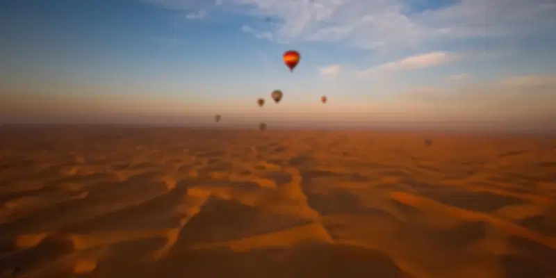 Desert balloon ride in Dubai soaring above the golden Margham Desert at sunrise, offering panoramic views of rolling sand dunes and an unforgettable adventure.