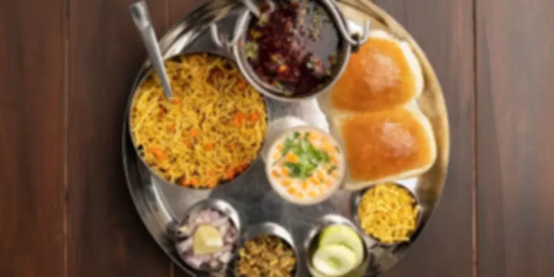 Traditional Gujarati thali with pav, curry, farsan, and sev served at Rasoi Ghar