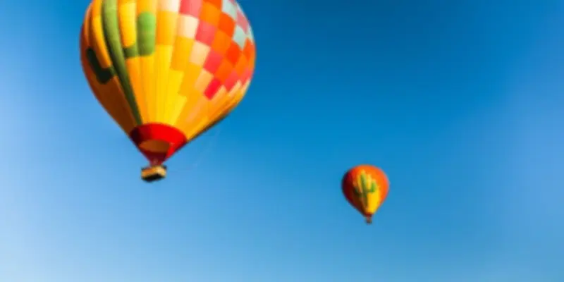 Colourful hot air balloons soaring through a clear blue sky during the best time for a hot air balloon ride in Dubai, offering spectacular sunrise views over the desert.